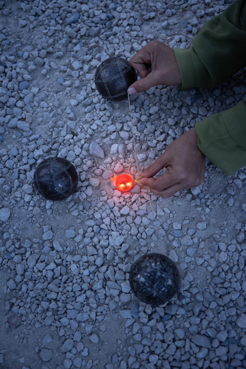 Cochonnet lumineux Cocholed orange posé sur le sol, un joueur le mesure avec une corde lors d'une partie de pétanque